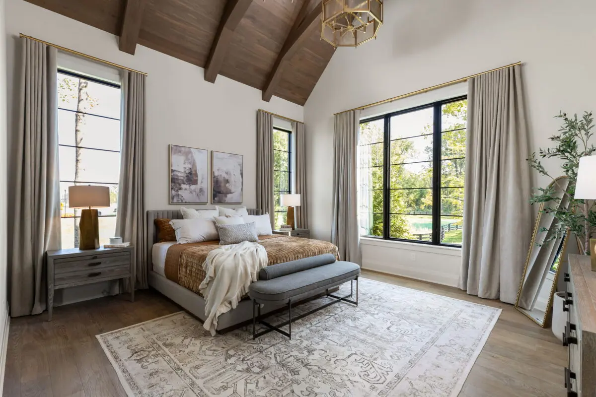 Primary bedroom with a vaulted beamed ceiling, black-framed windows and a tufted bench