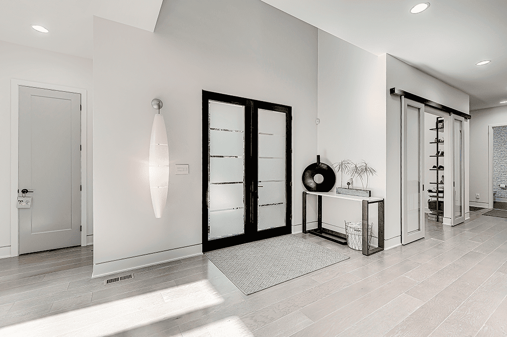 A modern entryway with a glass door and hardwood floors.