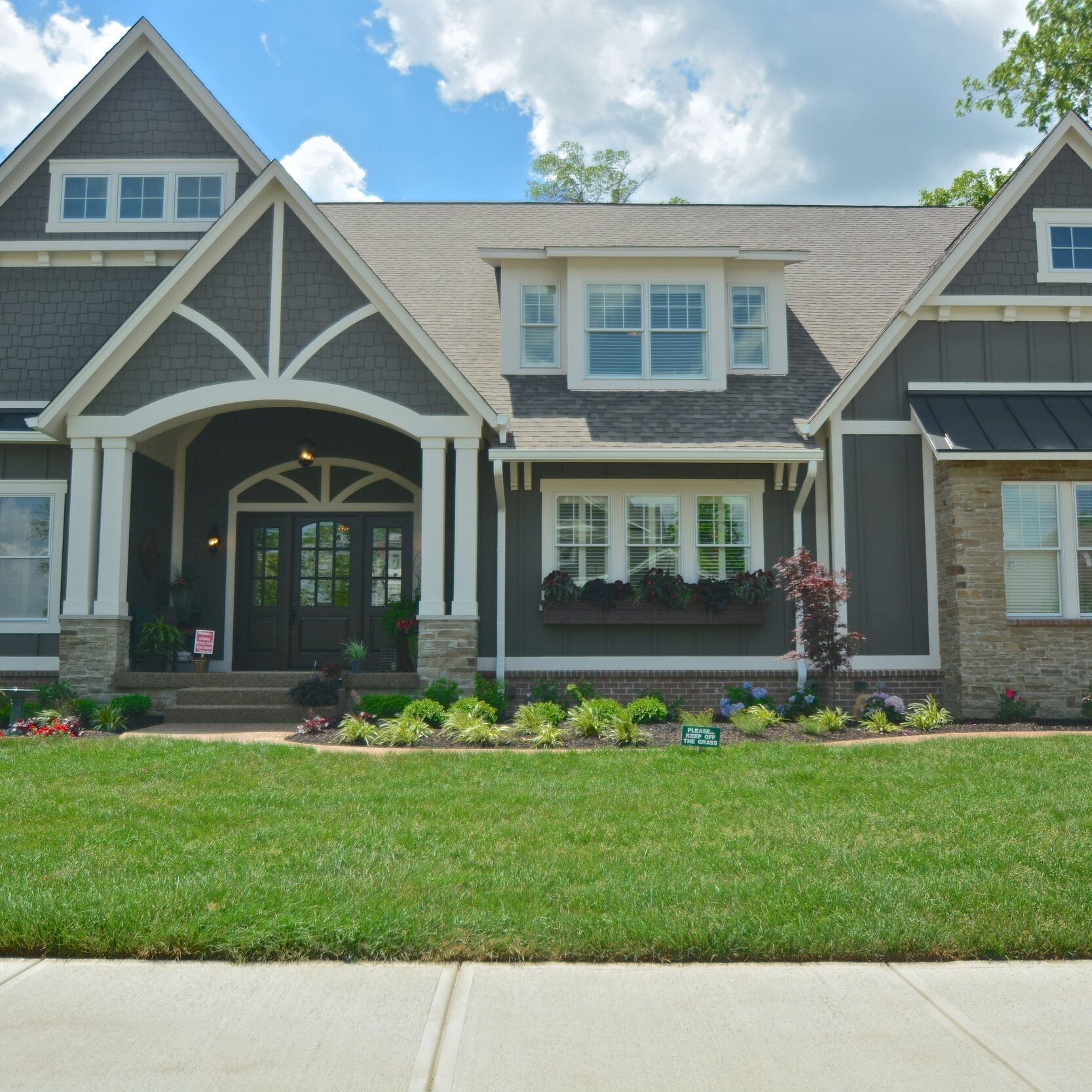 The exterior of a new home with gray siding and a green lawn, built by a custom home builder in Westfield.