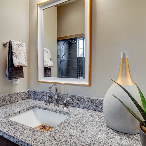 A bathroom with granite counter tops and a large mirror in a new home construction in Indianapolis.