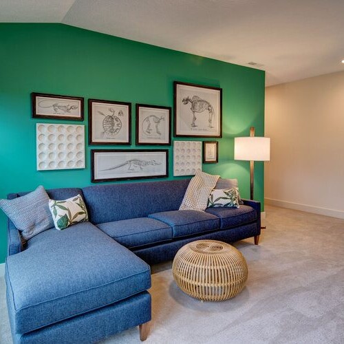 A living room with custom home builder green walls and a new home construction blue couch.