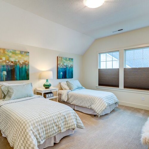 Two beds in a bedroom with white walls for sale.