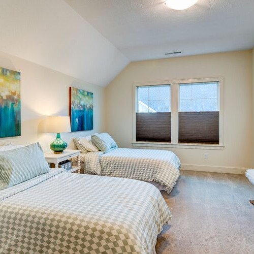 A bedroom with two beds and a painting on the wall, located in Westfield Indiana.