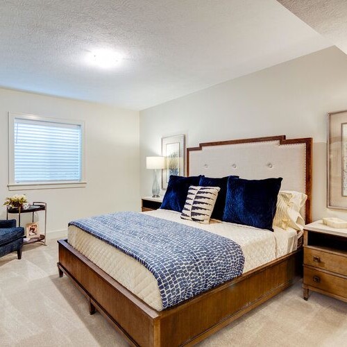 A bedroom with a bed and a chair, available in new homes for sale in Carmel, Indiana.