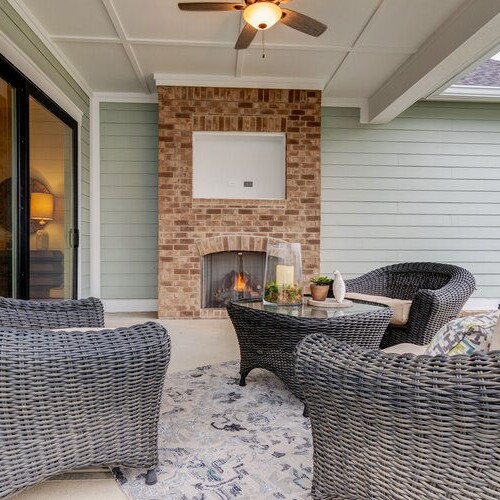 A patio with wicker furniture and a cozy fireplace.