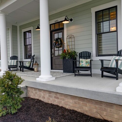 The front porch of a new home construction with black chairs.