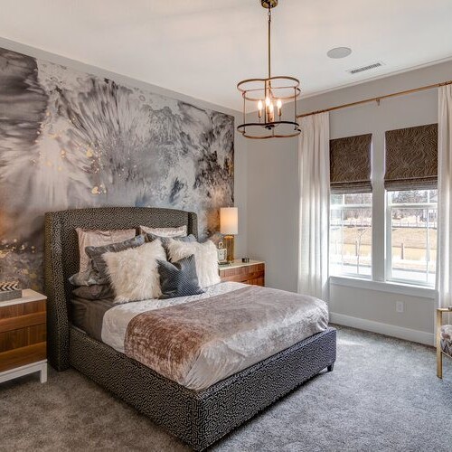 A bedroom with a gray bed and a large wall mural.