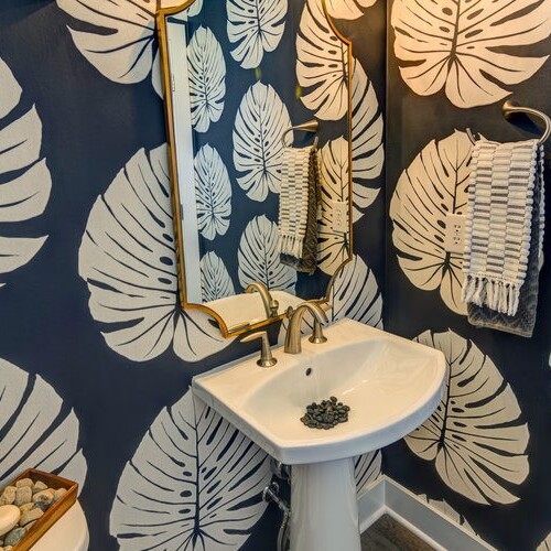 A bathroom with blue and white wallpaper and a gold sink.