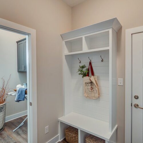 A white mudroom with a basket and a door.