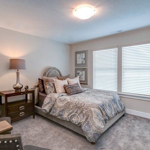 A bedroom with a bed and a chair next to a window.