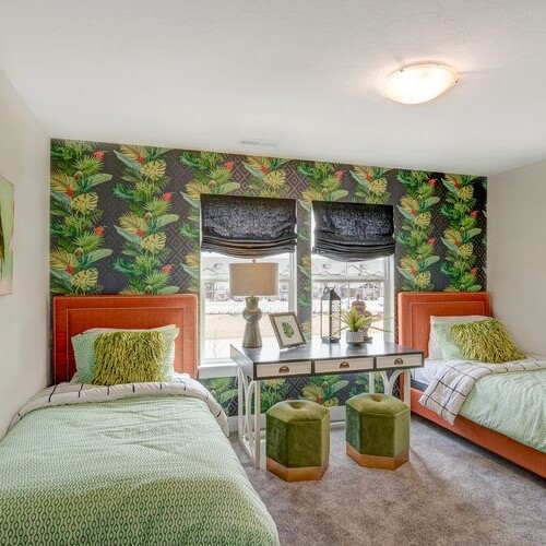 Two twin beds in a bedroom with green and orange accents.