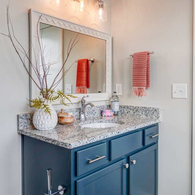 A bathroom with blue cabinets and granite counter tops.
