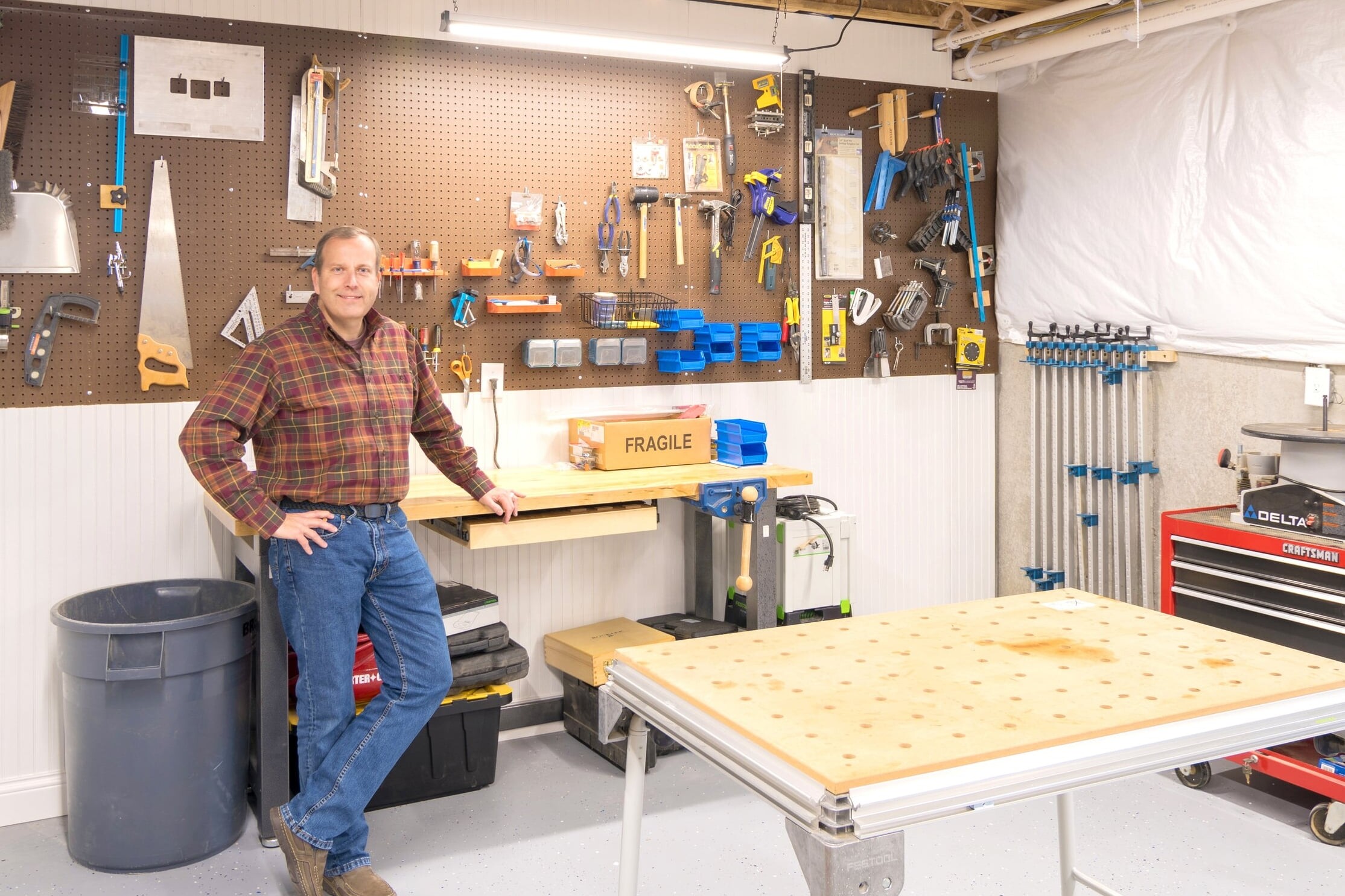 A man standing in front of a workbench in a garage, working on Indianapolis Custom Homes.