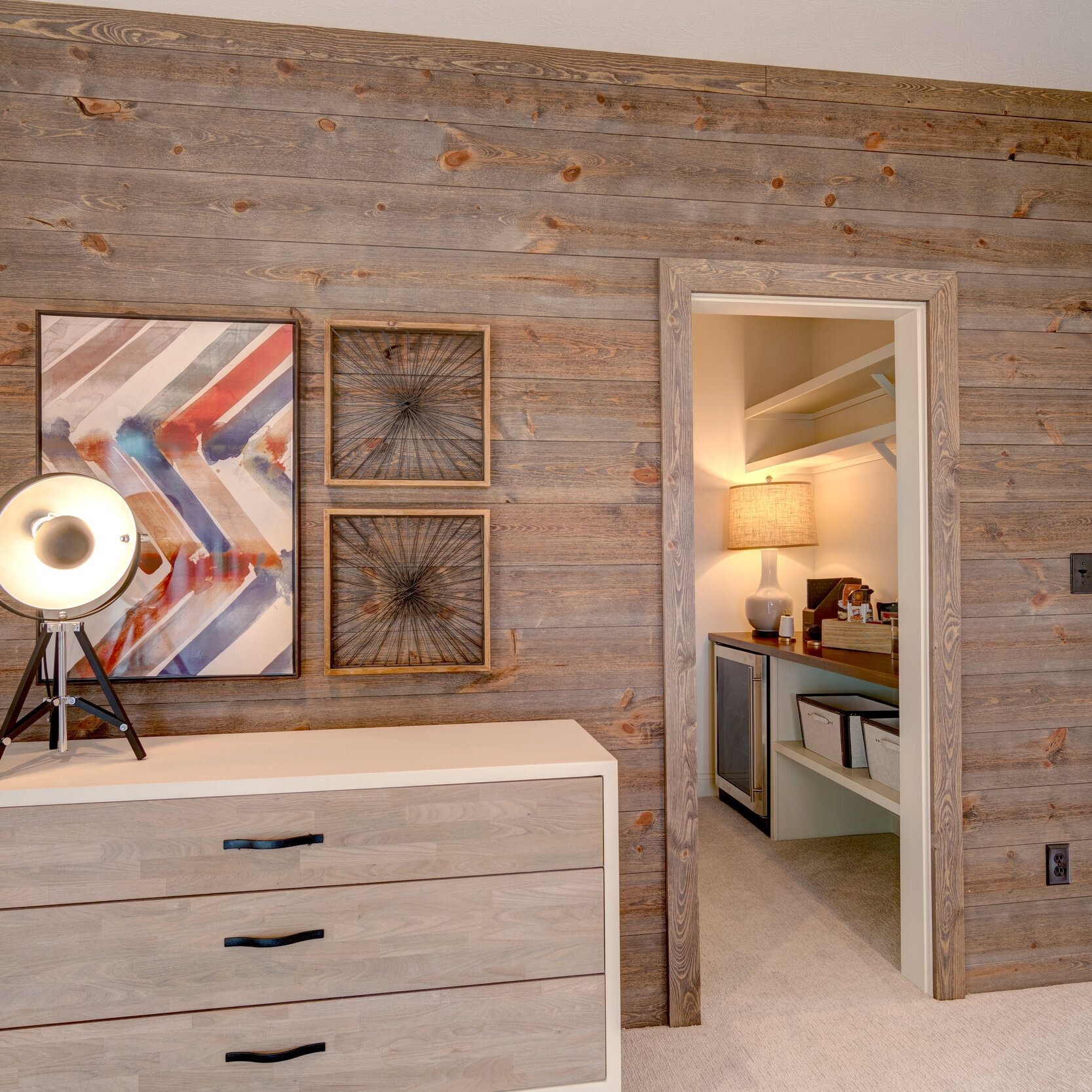 A bedroom with wood walls and a dresser in a custom home in Indianapolis.