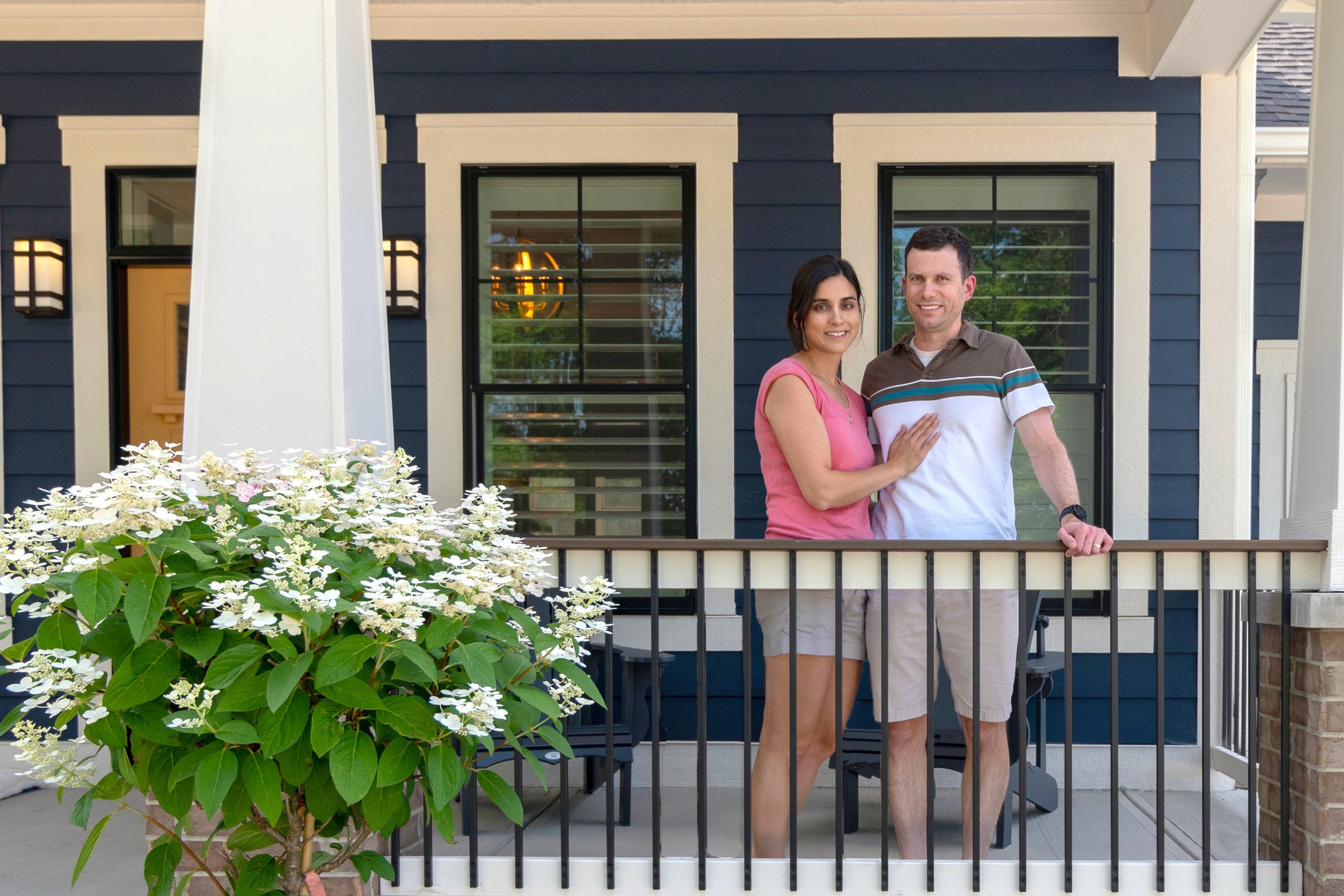 A couple standing on the porch of a newly built custom home in Carmel, Indiana.