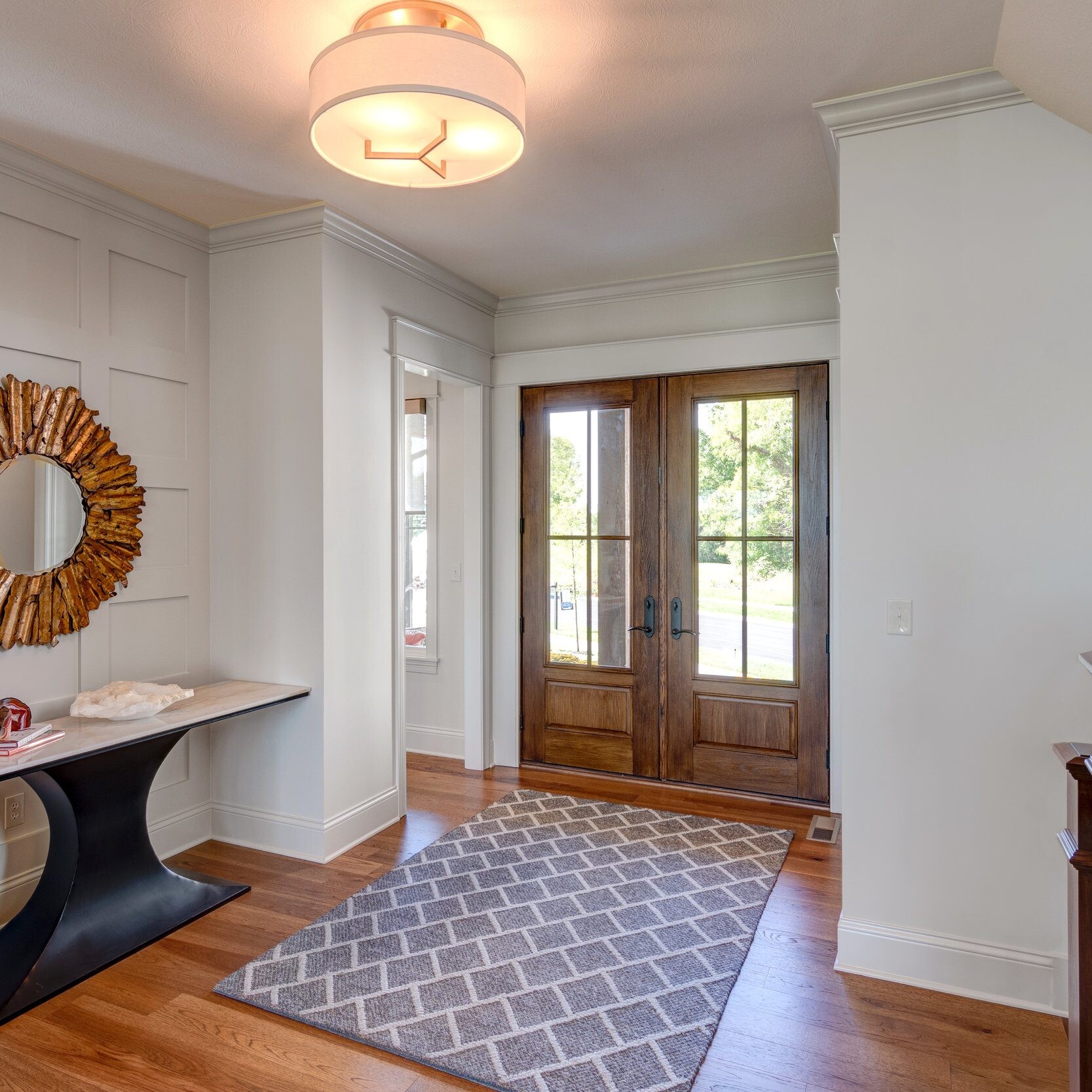 An entryway with hardwood floors and a large mirror in a new home construction in Indianapolis.