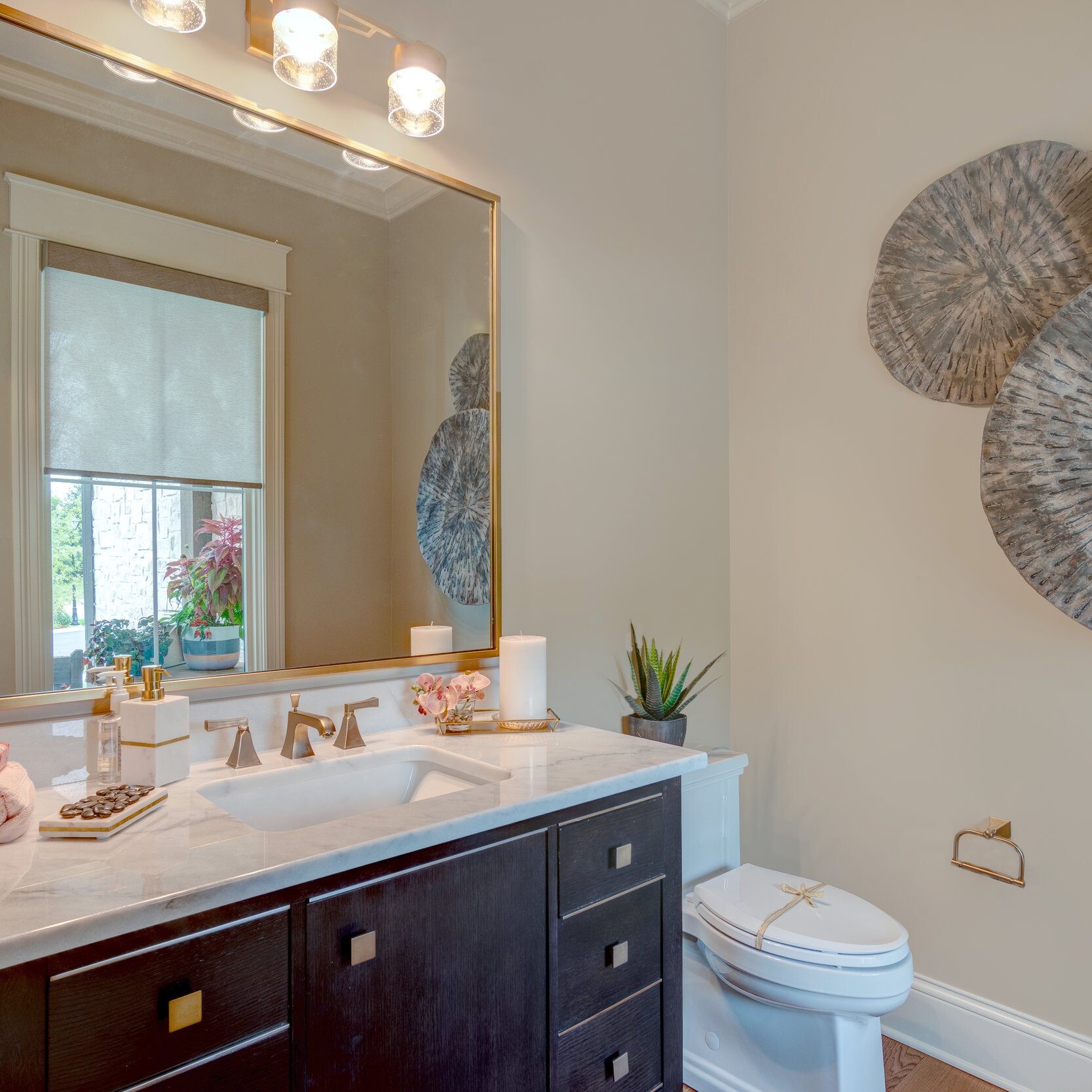 A new bathroom with a toilet, sink, and mirror in a custom home builder Carmel Indiana.