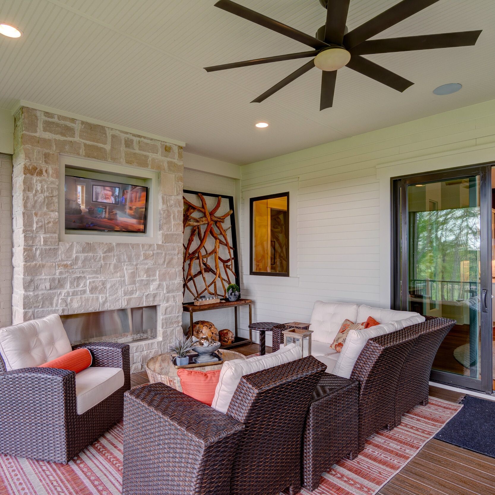 A patio with wicker furniture and a ceiling fan, designed by a custom home builder in Carmel Indiana.
