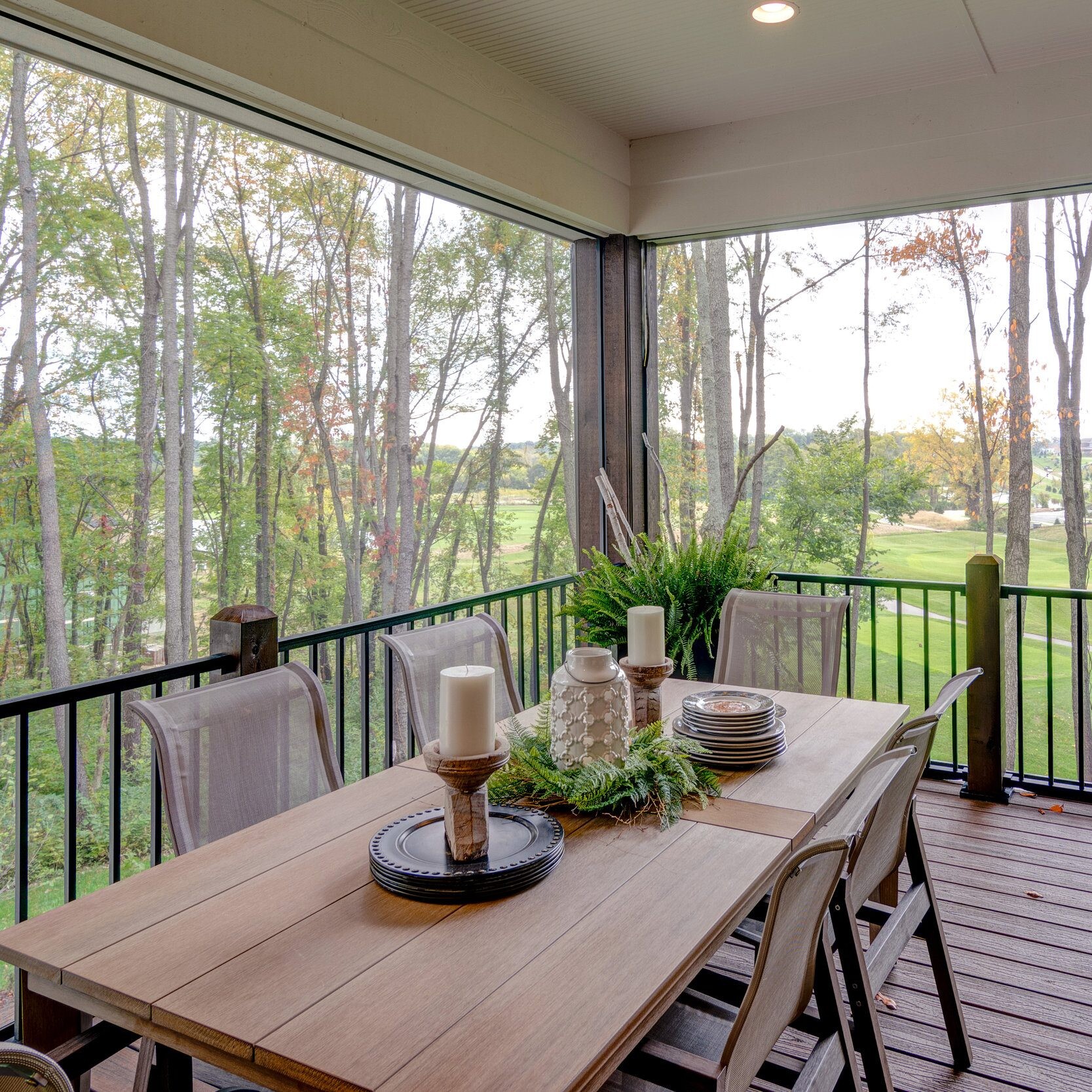 A deck with a table and chairs overlooking a wooded area, perfect for enjoying the natural surroundings of your new home in Carmel, Indiana.