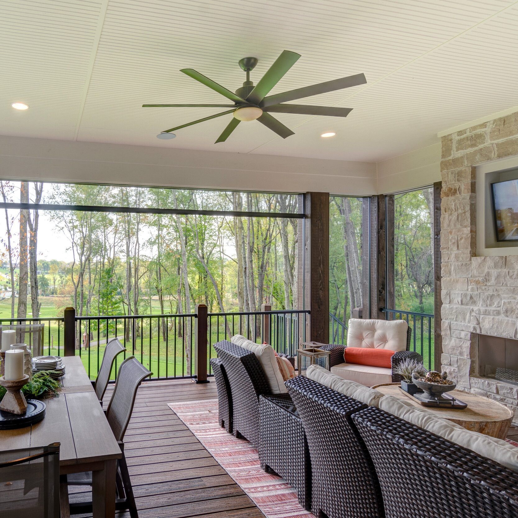 A covered patio with furniture and a ceiling fan, perfect for enjoying the outdoors in your custom home built by a reputable custom home builder in Carmel, Indiana.