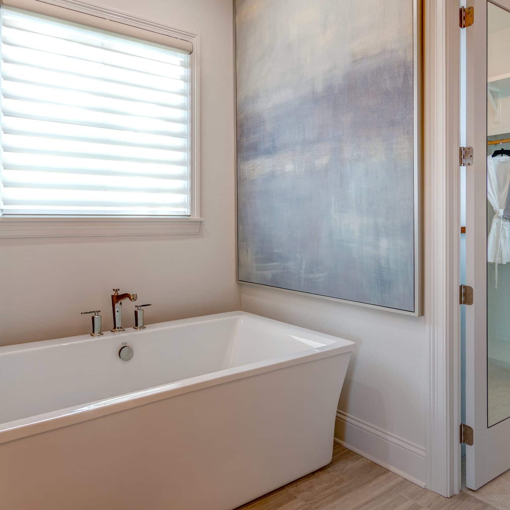 A white bathroom with a bathtub and closets in a custom home for sale in Westfield, Indiana.