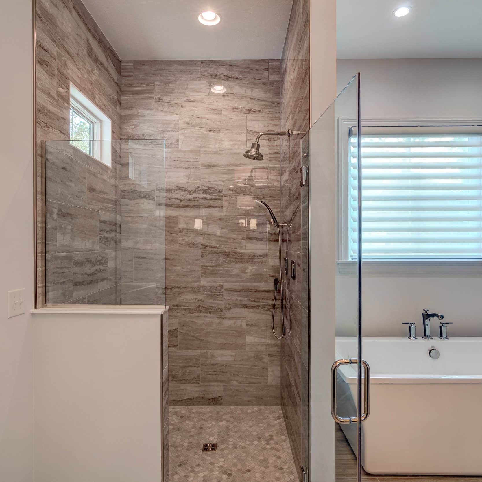 A bathroom with a glass shower stall and a bathtub in one of the new homes for sale in Carmel, Indiana.