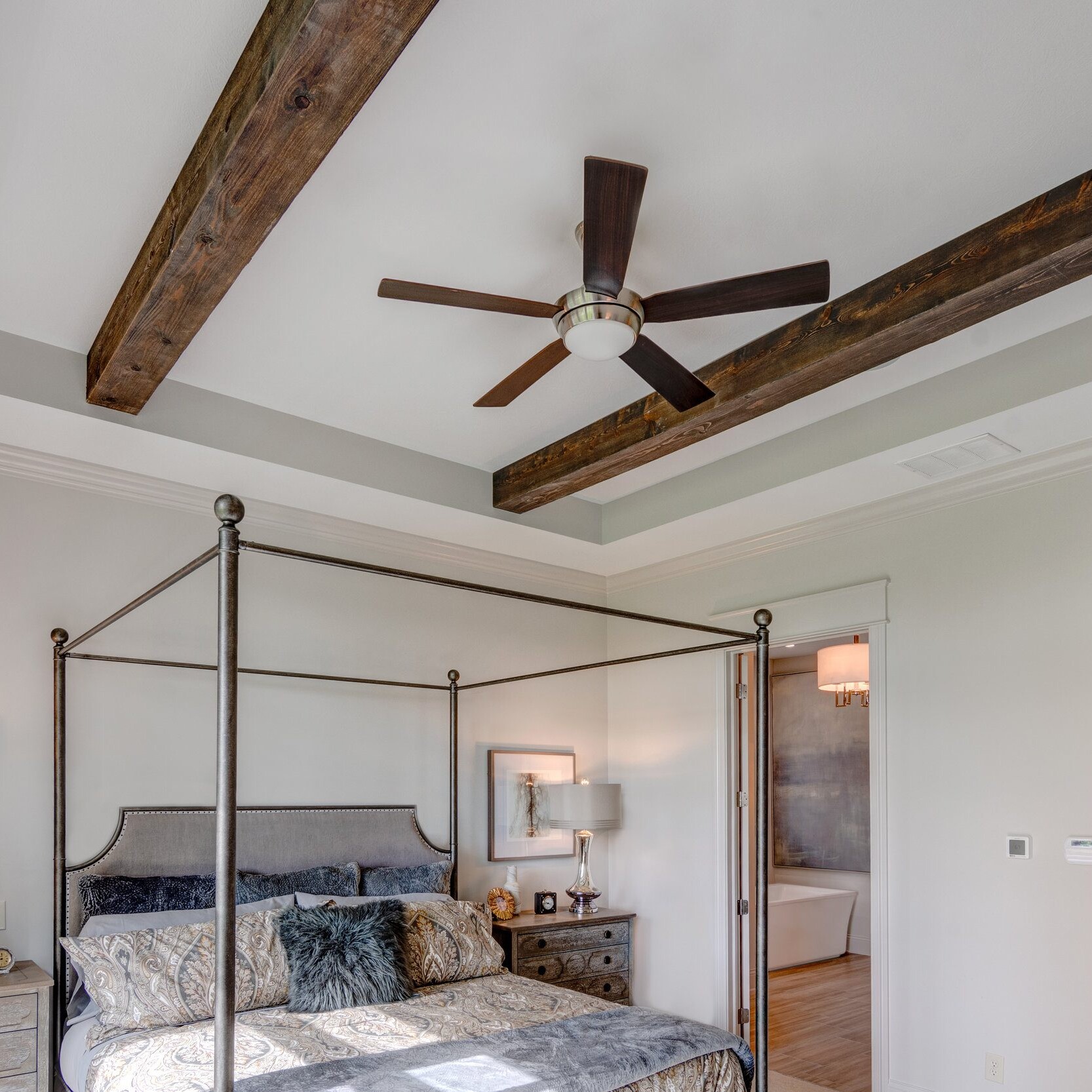 A bedroom with wood beams and a ceiling fan in a new home construction.