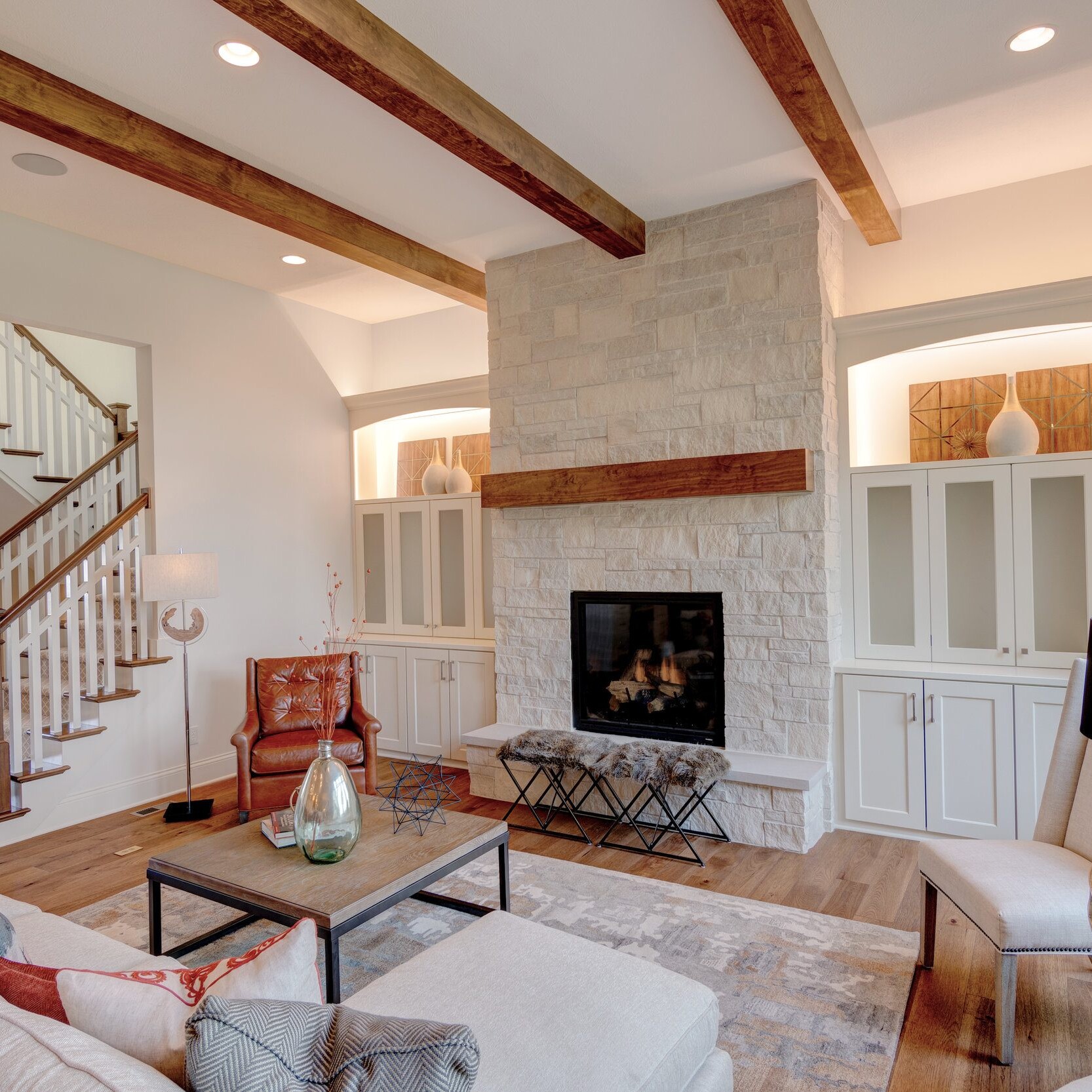 A living room with wood beams and a fireplace in a custom home.