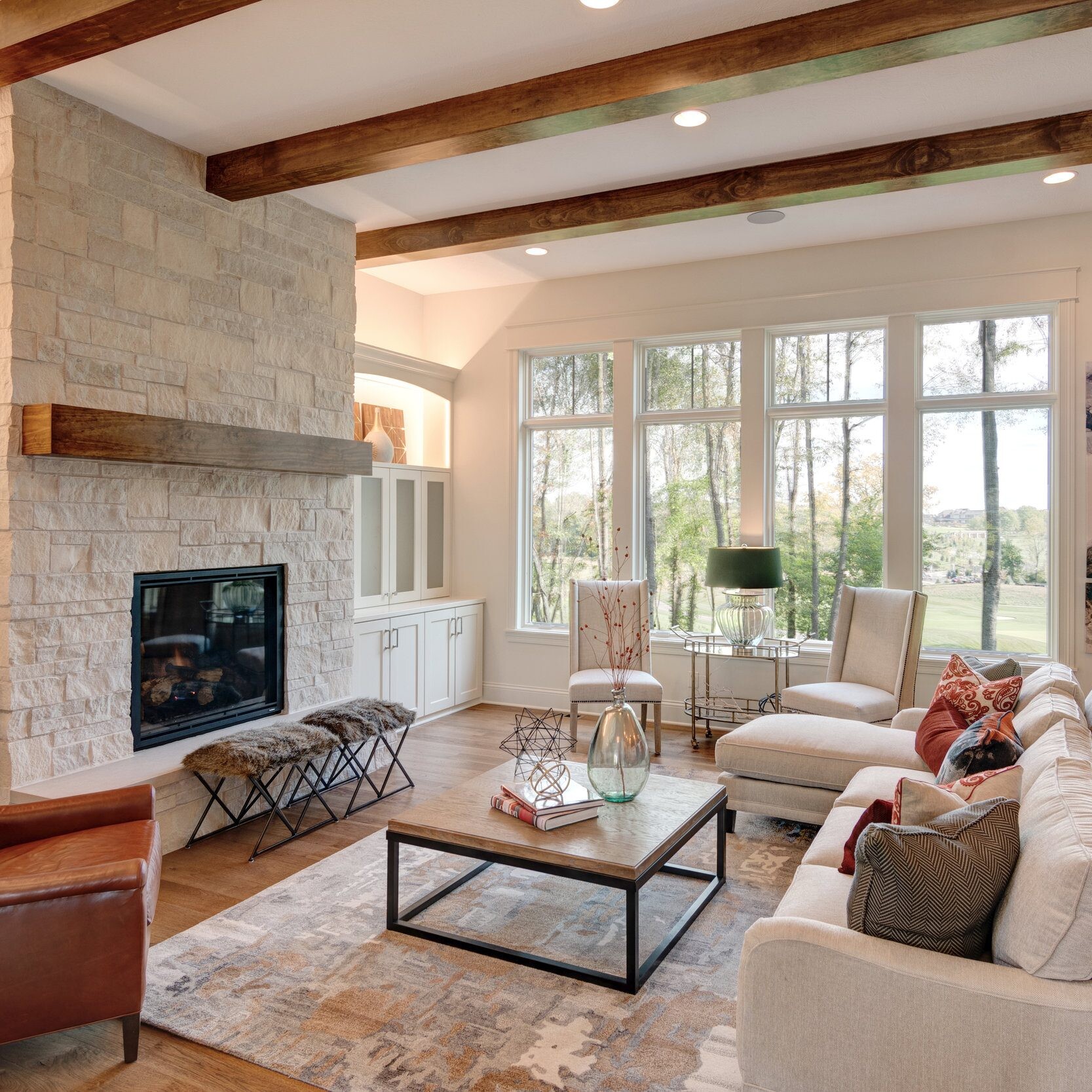 A cozy living room featuring a stone fireplace and charming wooden beams.