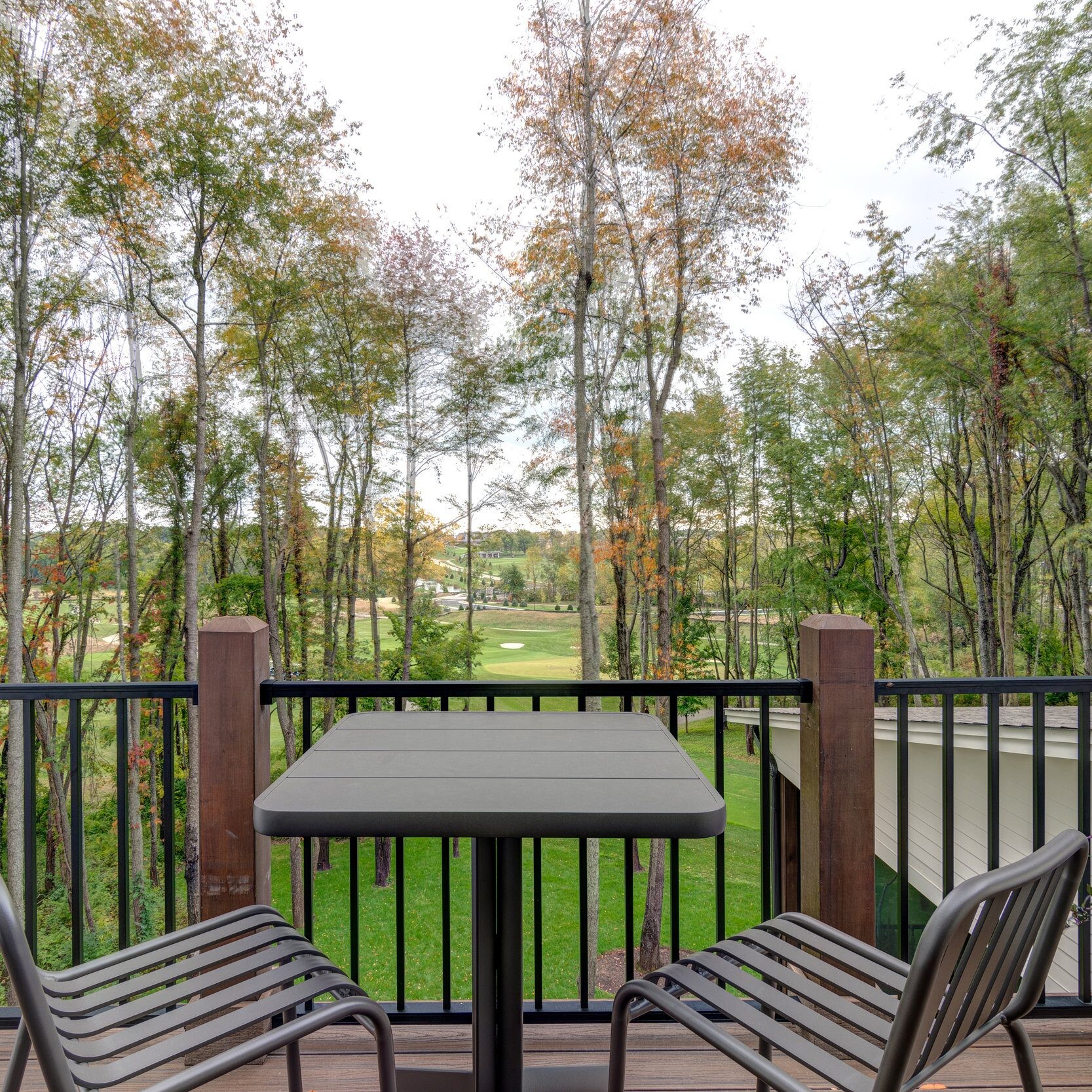 A custom-built deck with a table and chairs, offering picturesque views of a beautiful wooded area.