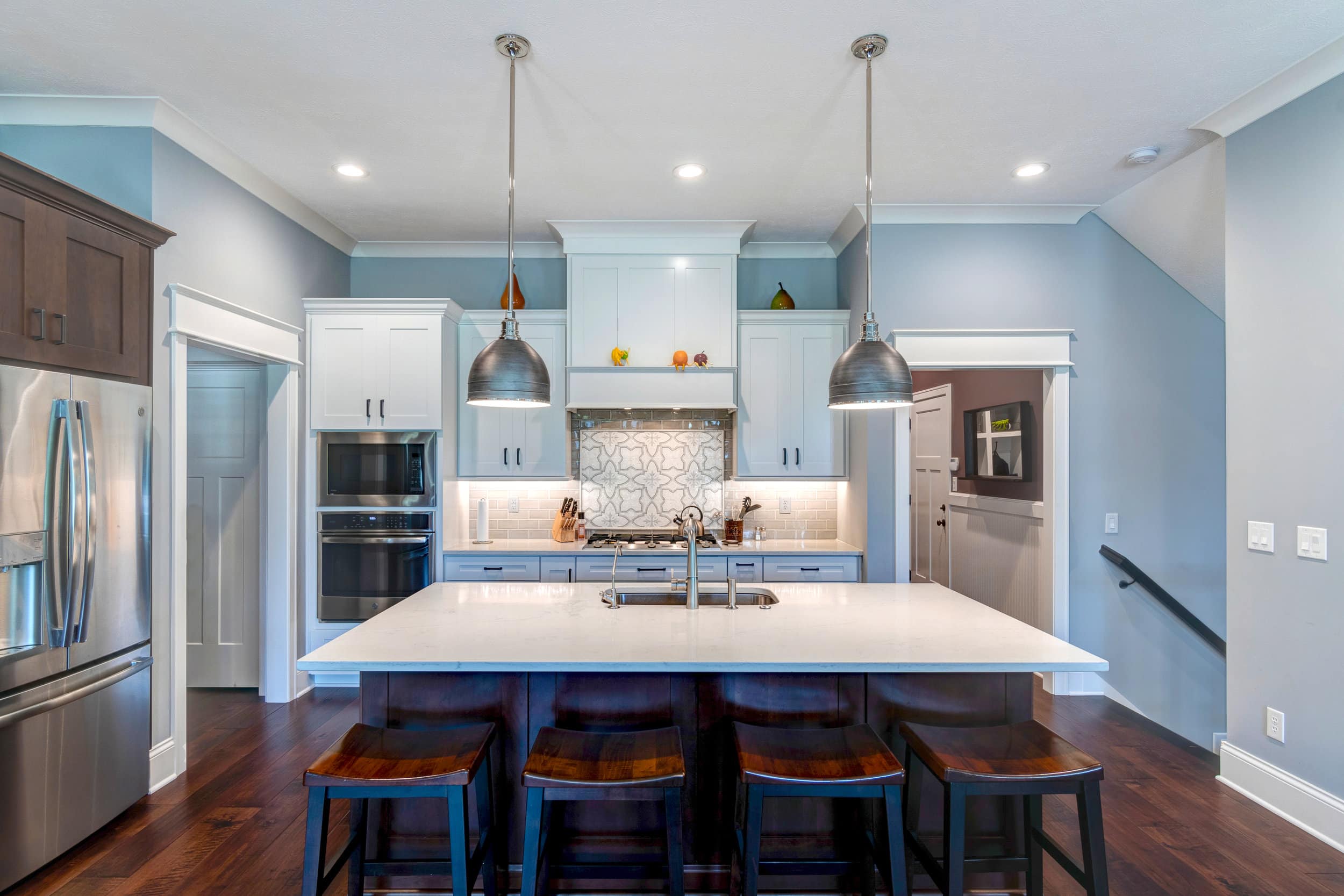 A kitchen with blue walls and stainless steel appliances, designed and built by a trusted Custom Home Builder Carmel Indiana.