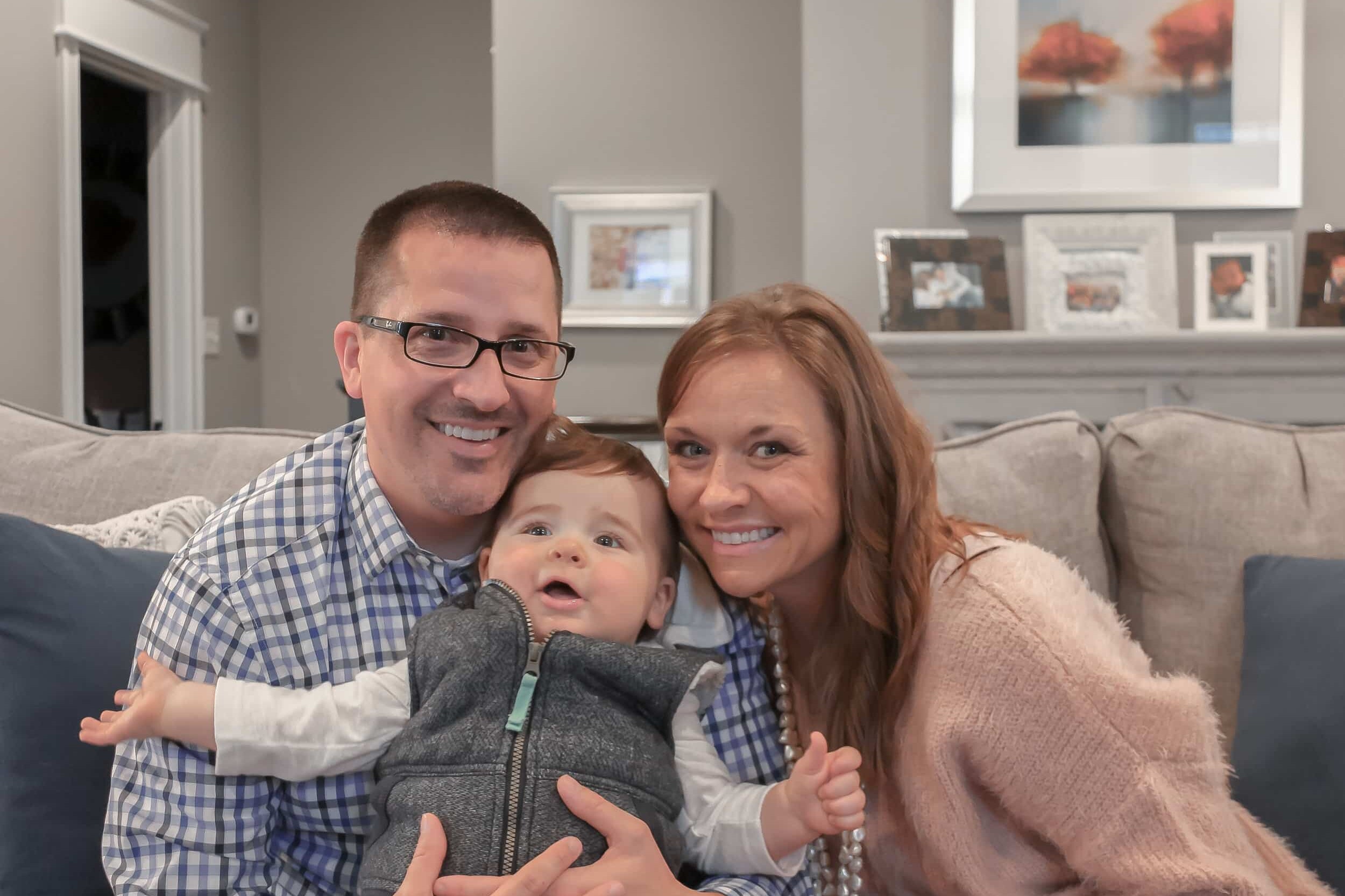 A man and woman cradling a baby on a couch in their new custom home.
