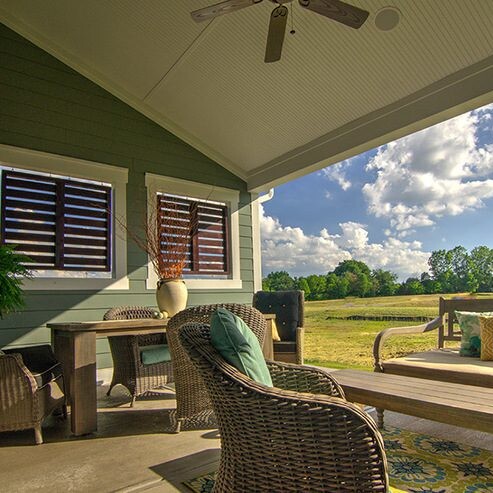 A patio with wicker furniture and a ceiling fan, built by a luxury custom home builder in Carmel Indiana.
