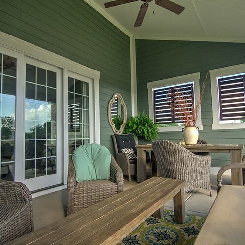 A porch with wicker furniture and a ceiling fan, perfect for relaxing in your custom home in Indianapolis Indiana.