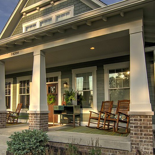 A custom home with a rocking chair on the front porch in Carmel Indiana.