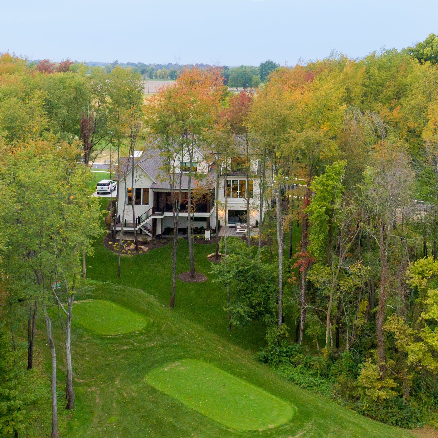 An aerial view of a golf course nestled amidst lush trees.