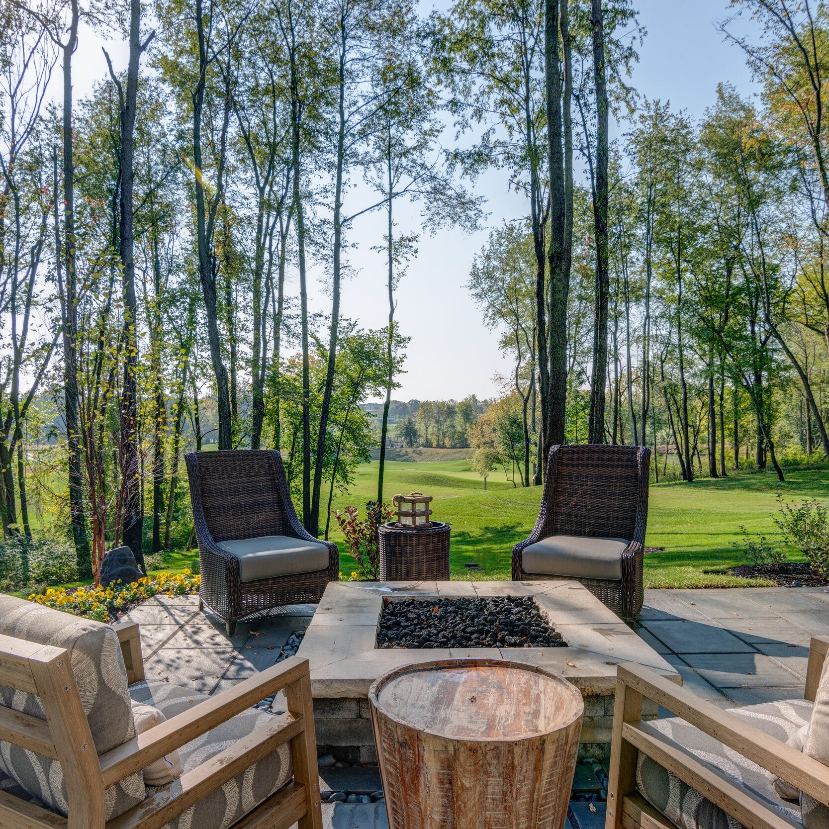 A spacious patio with a fire pit nestled in the midst of a serene wooded area.