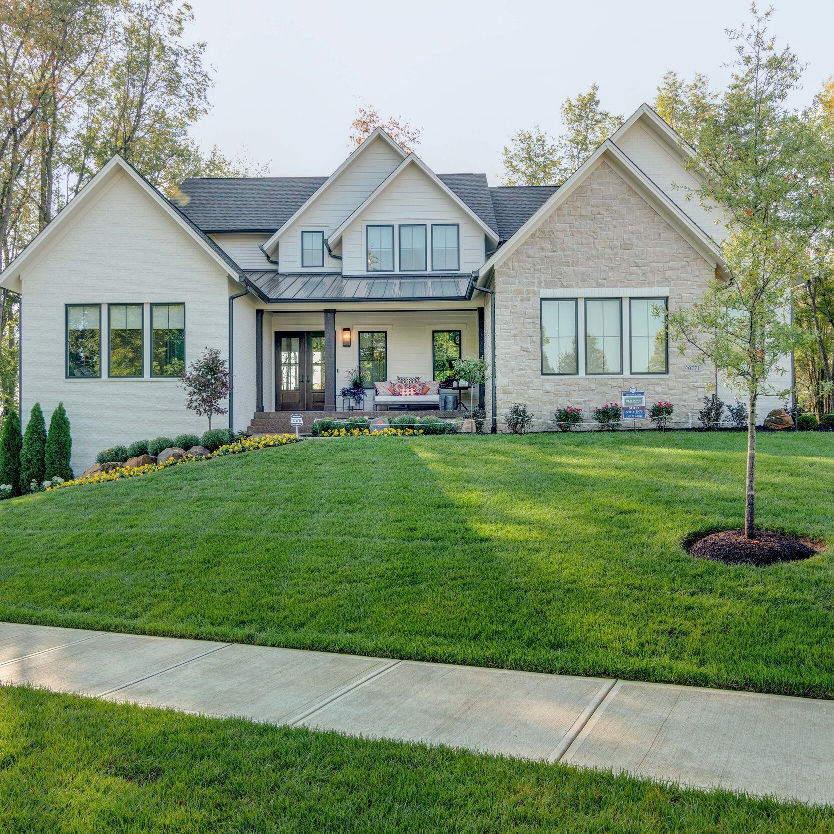 A custom home with a lawn and trees in the front yard, located in Carmel, Indiana.