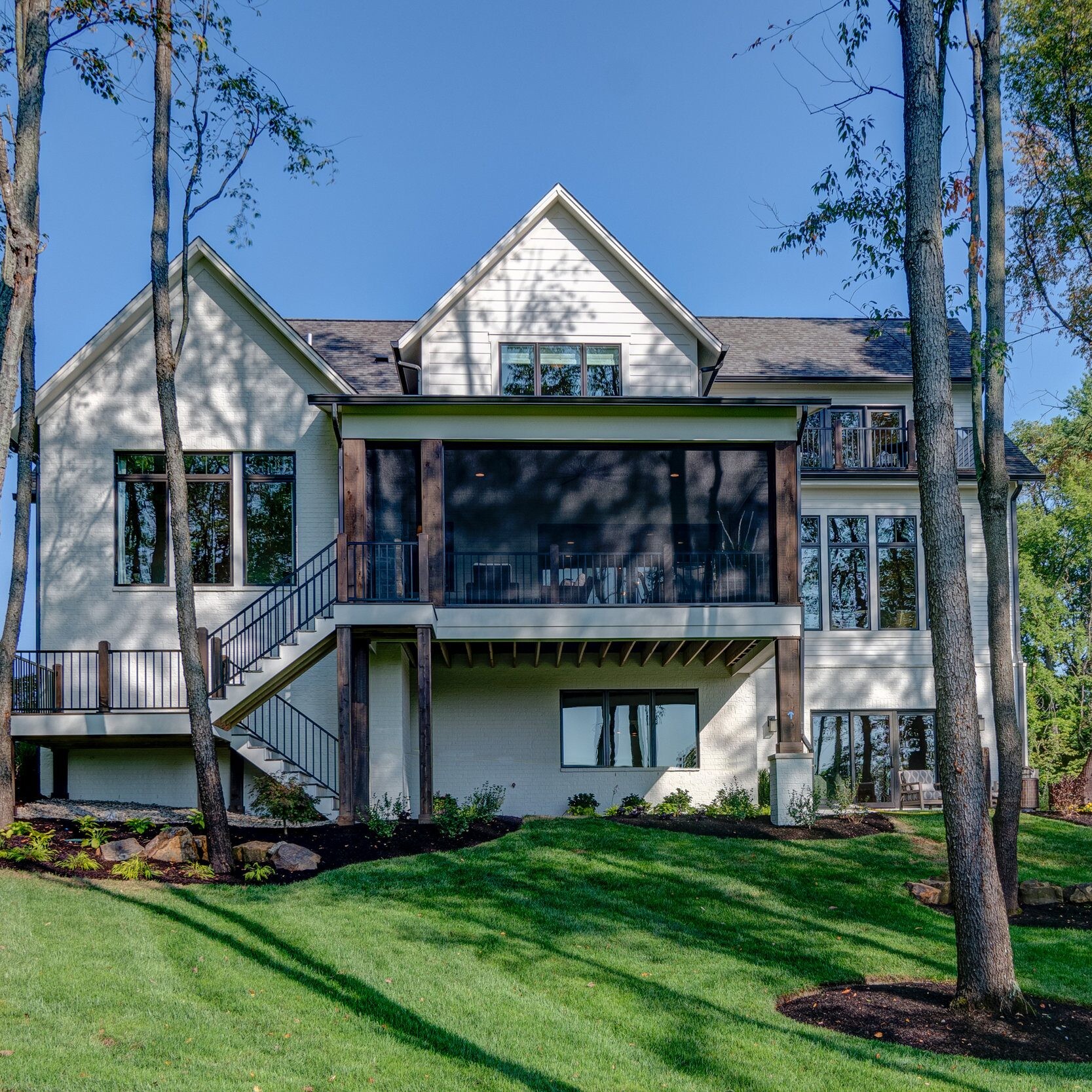 A custom home for sale in Westfield, Indiana with a large deck surrounded by beautiful trees.