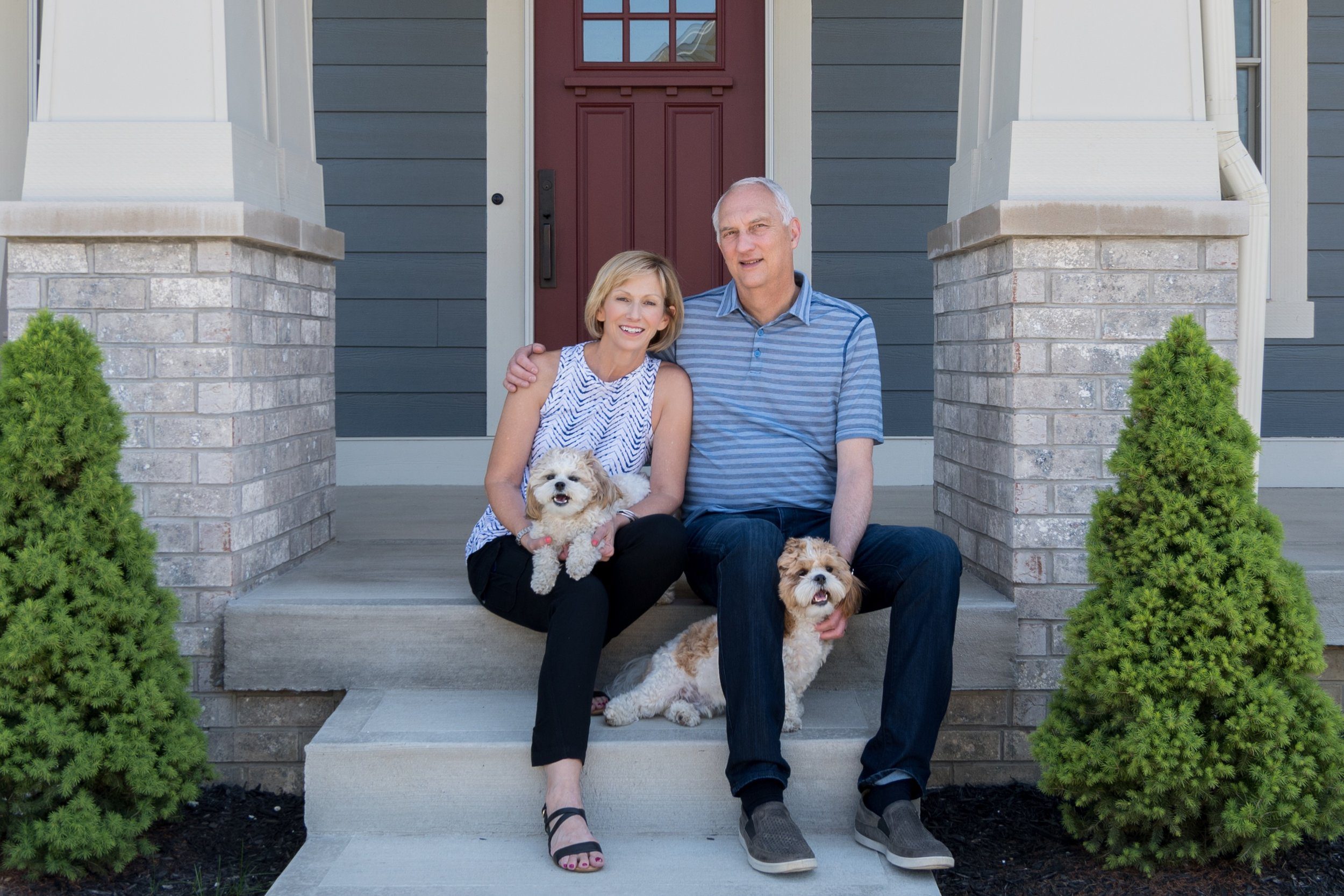 A couple and their dogs lounging on the steps of their new home.