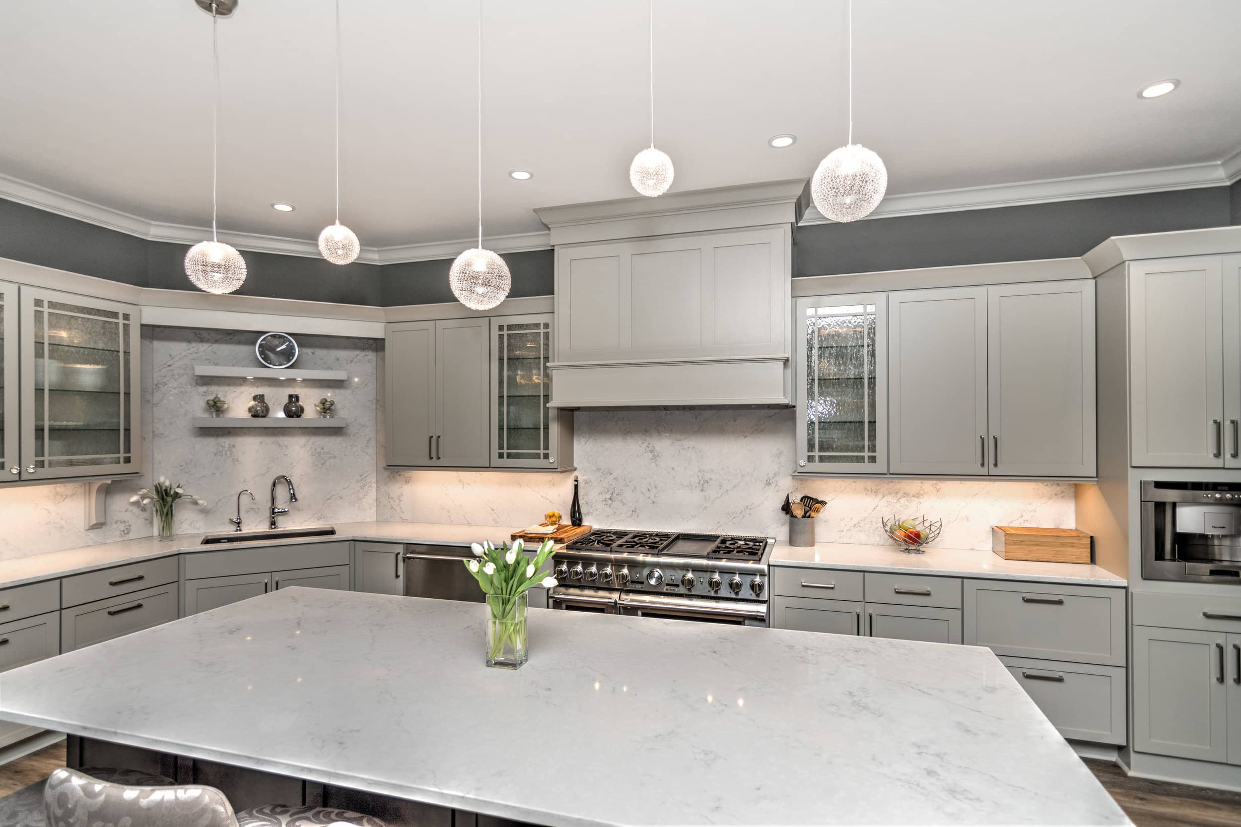 A custom kitchen with gray cabinets and marble counter tops designed by a Custom Home Builder Carmel Indiana.