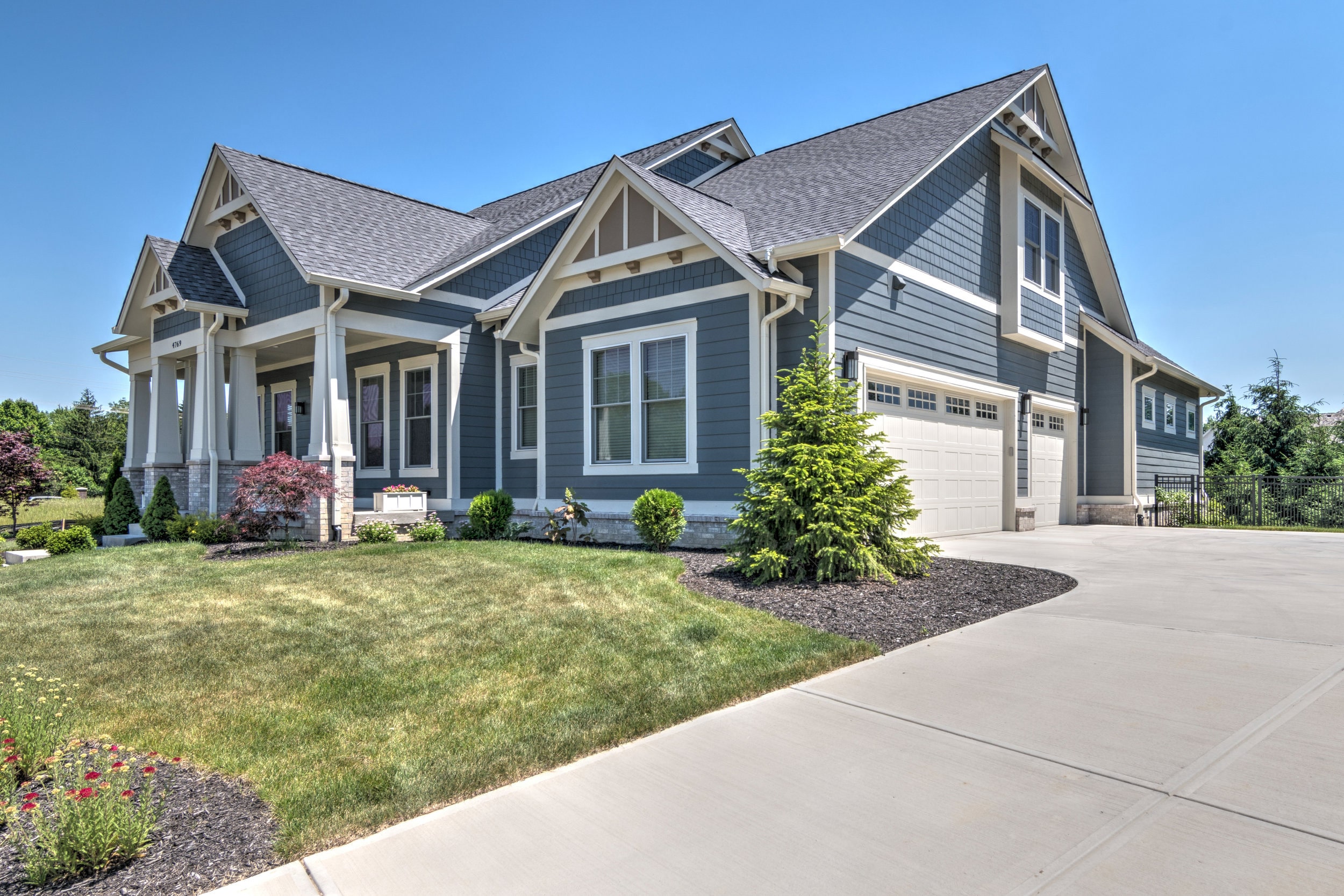 A custom home with blue siding and a driveway in Indianapolis.