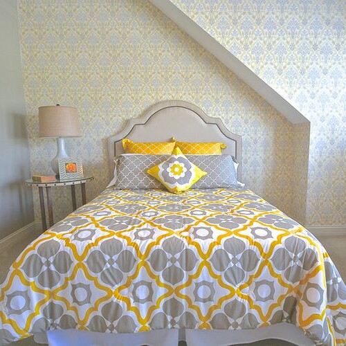 A yellow and gray bedroom with a bed and a chair in a new home construction in Indianapolis, Indiana.