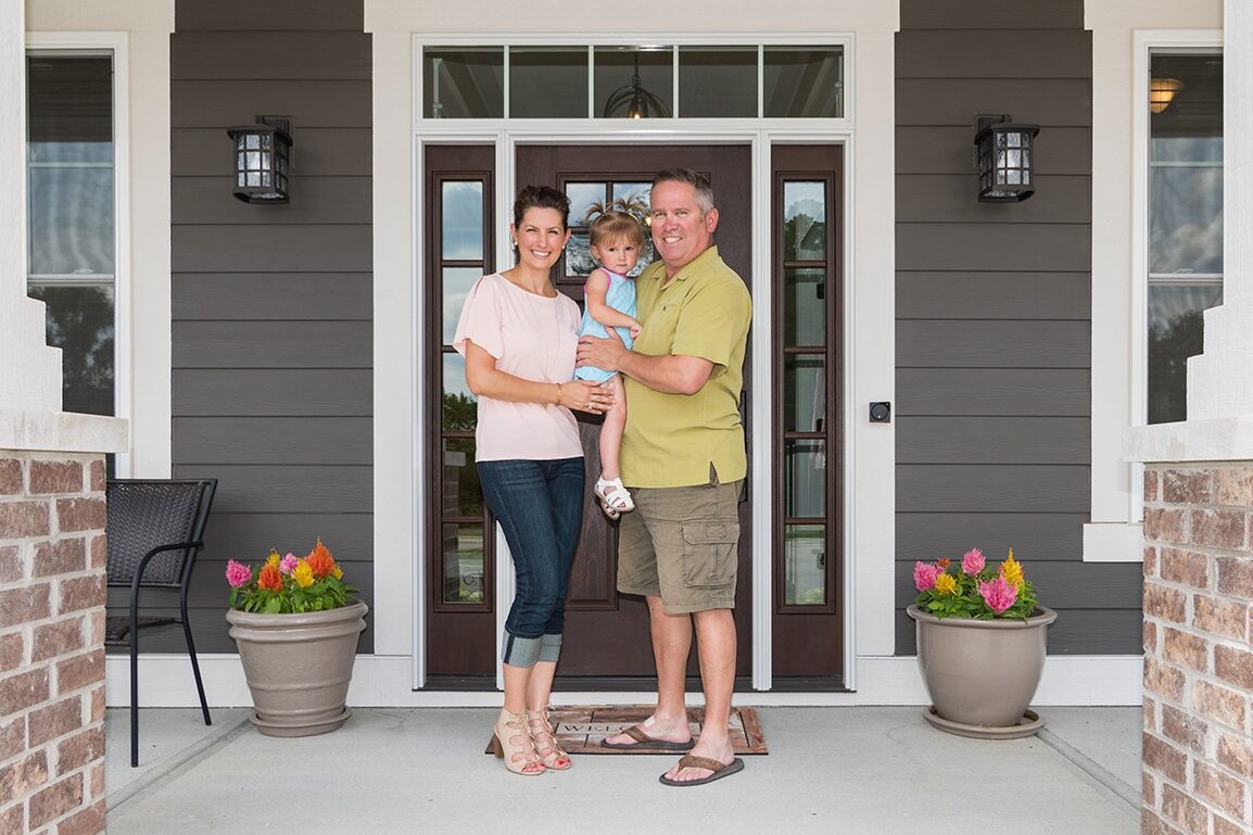 A family standing in front of their new custom home.
