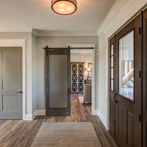 A hallway with wooden floors and a wooden door in a new home construction.