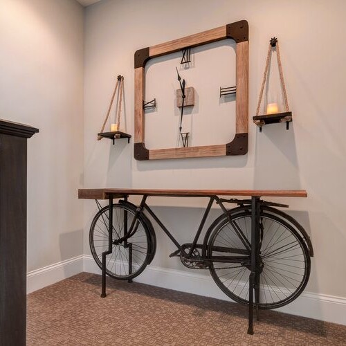 A custom home builder carmel indiana showcases their exceptional craftsmanship with a stunning wooden table adorned with a vintage bicycle as decor. The space is further enhanced by a functional wall clock, adding an