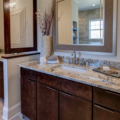 A bathroom with granite counter tops and wooden cabinets, featured in new homes for sale in Carmel Indiana.