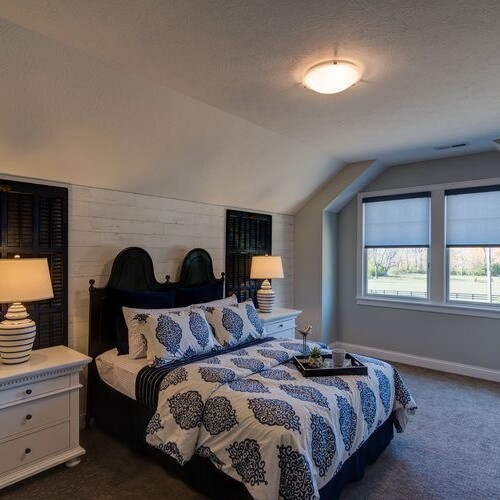 A cozy bedroom with a modern bed, dresser, and nightstand in one of the new homes for sale in Carmel, Indiana.