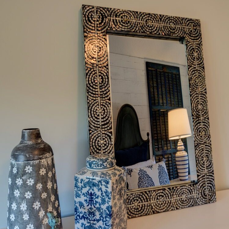 A mirror and a vase displayed on a dresser.