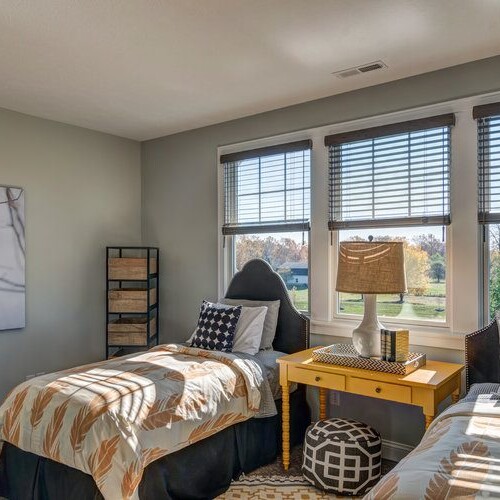 A bedroom with two twin beds and a window in a new home construction in Indianapolis, Indiana.